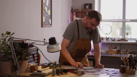 leathersmith sharpens small cutter for leather on table