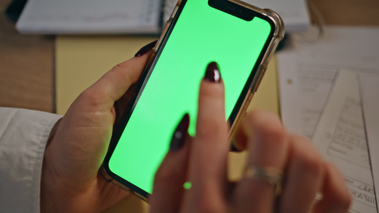Businesswoman hands typing greenscreen smartphone at evening office closeup
