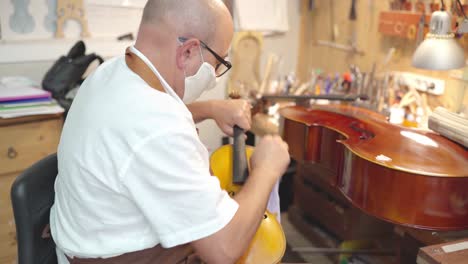 craftsman with violin in professional workshop