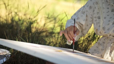 young female artist paints round picture in small studio