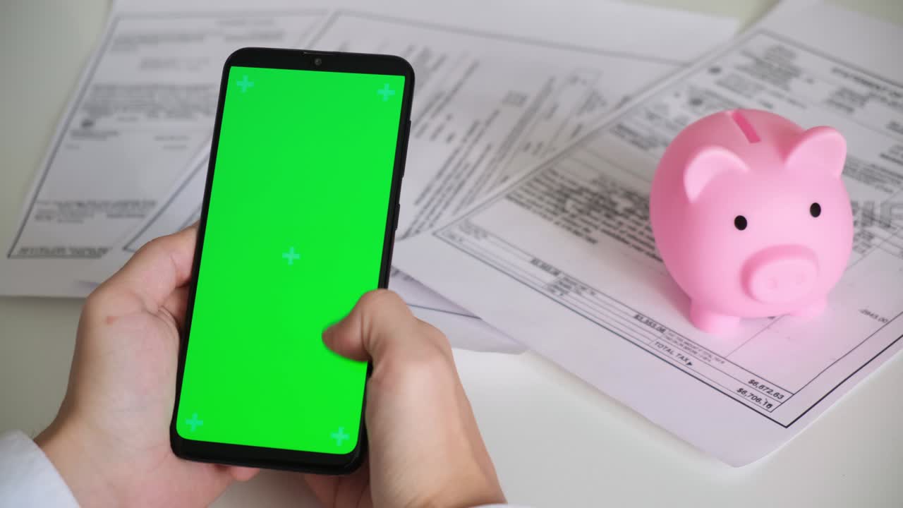 teléfono con pantalla verde y recibos de pago de banco de cerdos, documentos fiscales en fondo blanco vista superior. teléfono inteligente chromakey desliza en diferentes direcciones. espacio de copia