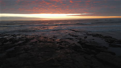 Low-Establishing-Aerial-Drone-Shot-Over-Beach-and-Sea-at-Stunning-Sunrise-in-North-Yorkshire-at-Low-Tide-UK