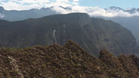 Stunning-arid-landscape-with-steep-cliffs-and-deep-valley-with-aerial-view-of-damn-in-distance