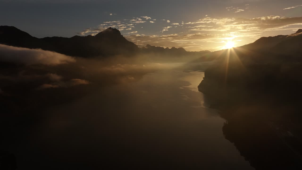 Golden sunrise over calm Walensee with silhouetted Swiss Alps, Switzerland