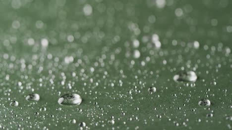 Micro-video-of-close-up-of-water-drops-with-copy-space-on-green-background