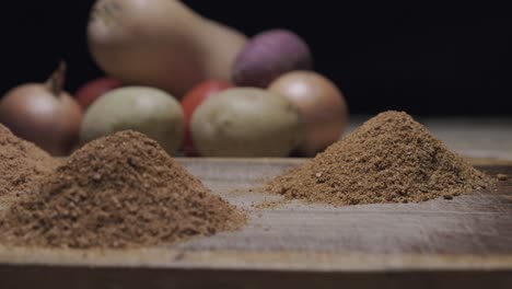 Close-up-left-pan-of-spice-heaps-with-vegetable-in-the-background