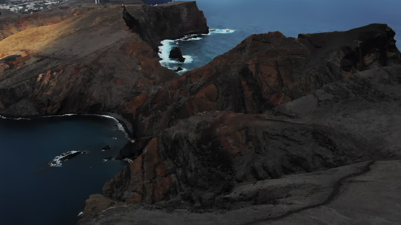 Explore breathtaking cliffs along a coastal shore, where the sun casts warm light on the landscape. Waves crash against the rocks, creating a serene atmosphere at dusk