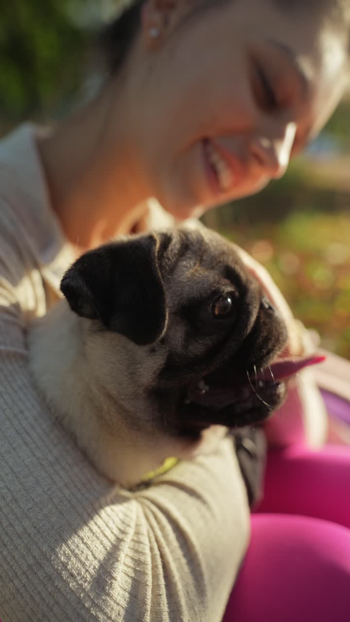 una mujer abrazando a un perro pug