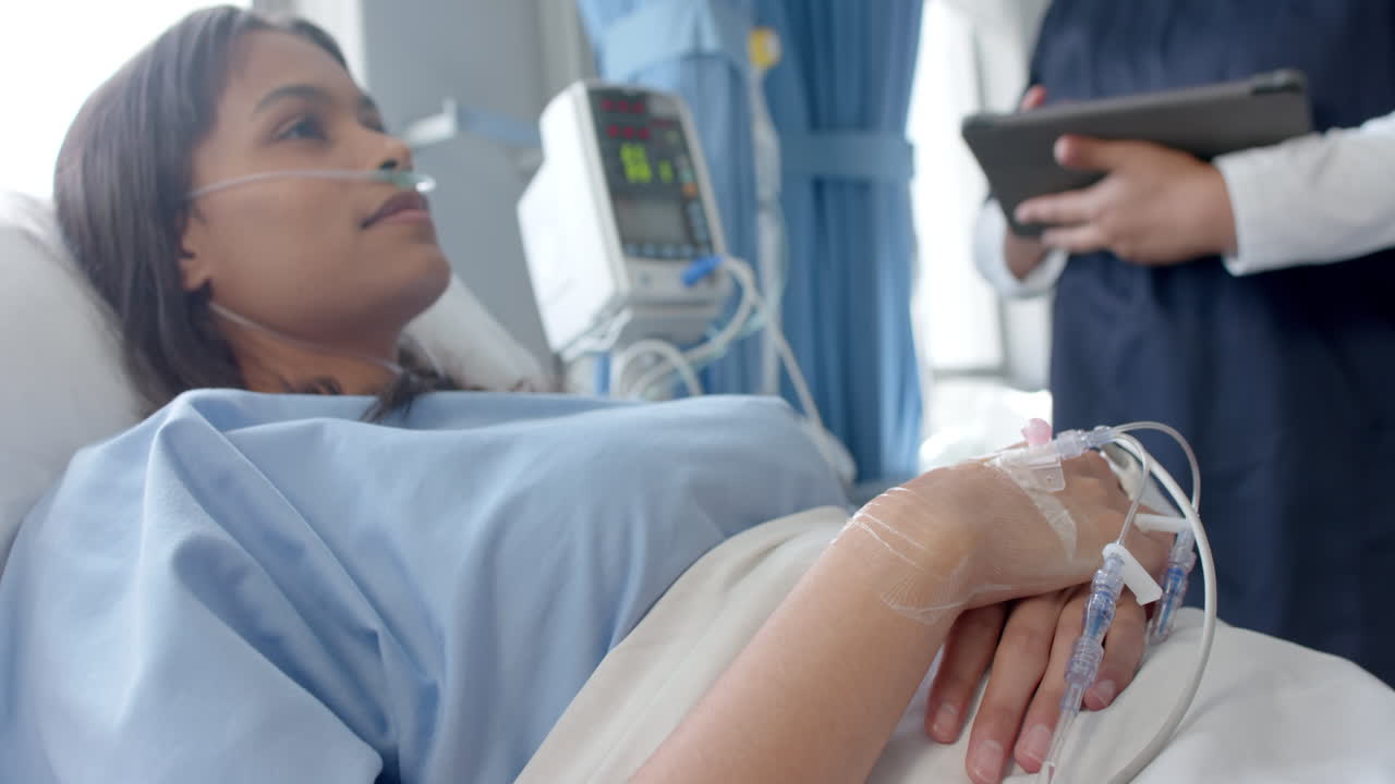 paciente femenina diversa en la cama del hospital y médico femenino usando tableta en la sala del hospital, cámara lenta