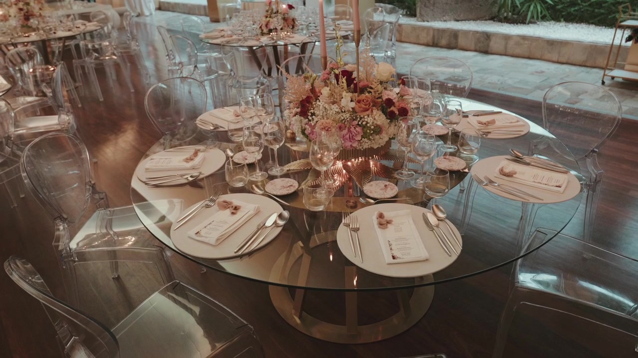 Elegant wedding reception table is set for dinner with fine tableware, floral centerpiece, and candlelight creating a festive atmosphere