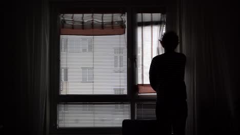 silhouette of a man slowly opening the window curtains - close up shot