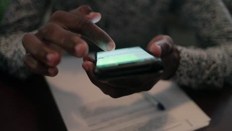 Male-hands-using-smartphone-above-table-with-papers