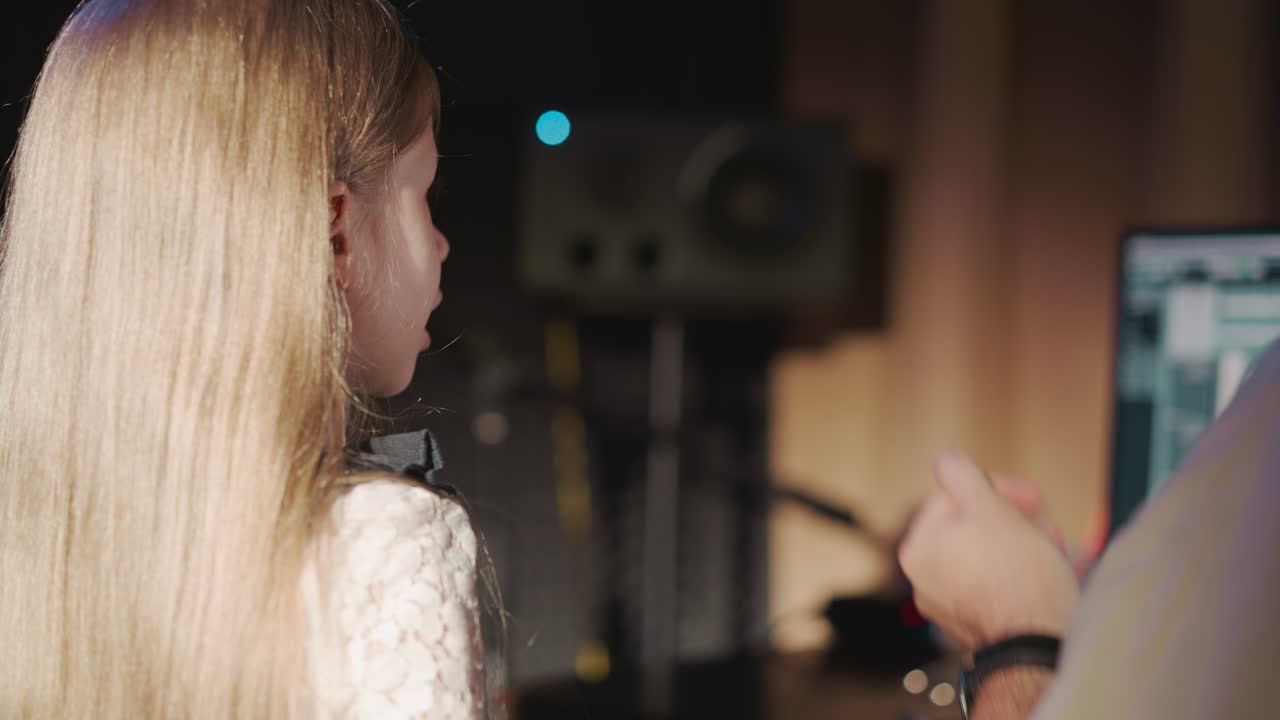 maestra vocal y niño en el estudio de grabación de primer plano. niña canta mientras el mentor chasquea el dedo realizando el ritmo. habilidades de sonido y ritmo