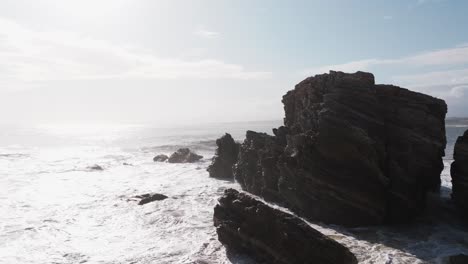 Bright-sunlight-illuminates-whitewash-from-waves-crashing-on-rocky-cliffs-of-Puerto-Escondido-Oaxaca-Mexico