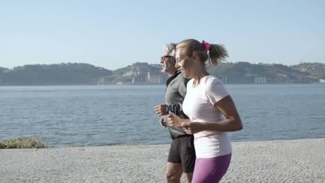 active couple training, jogging along sea and smiling