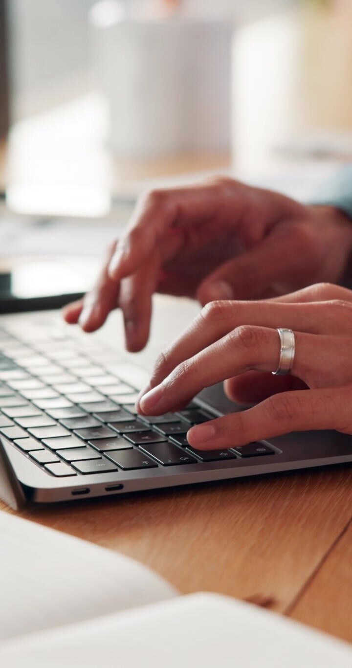 Primo piano di una persona che digita sulla tastiera del laptop in ufficio