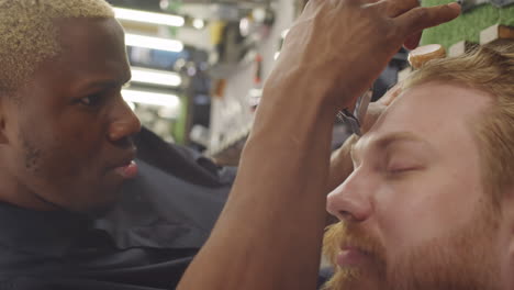 Black-Barber-Doing-Eyebrows-of-Man-with-Trimmer