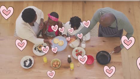 Animation-of-pink-hearts-over-happy-african-american-grandparents-and-grandchildren-cooking-at-home