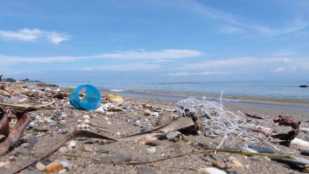 Beach with plastic and other trash waste and local fishermen in fishing canoe on tropical island destination