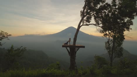 Frau,-Die-Sich-In-Kamelpose-Auf-Einer-Holzplattform-Mit-Magischem-Blick-Auf-Den-Berg-Agung-Nach-Hinten-Beugt,-Moment-Des-Zen