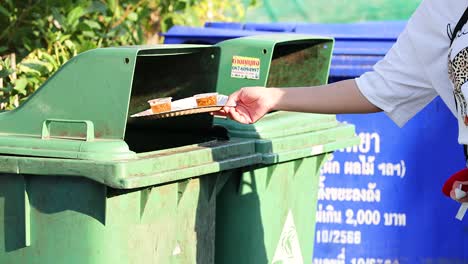 persona que elimina la basura en el contenedor verde