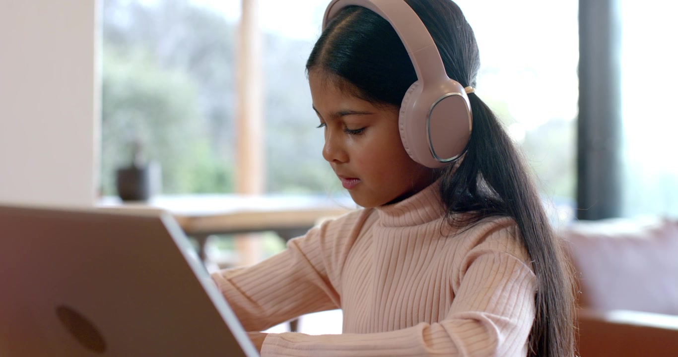 Young Girl Wearing Headphones Using Laptop for Online Learning