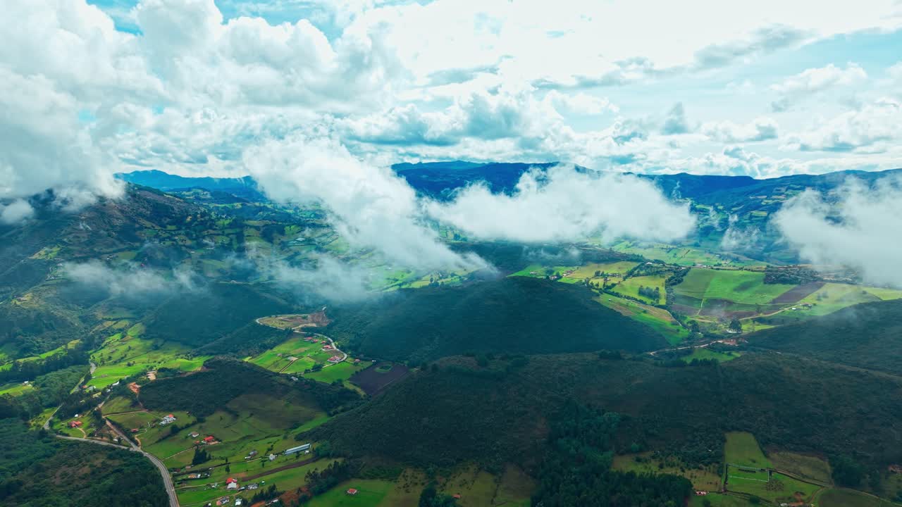 Aerial view of clouds above mountains and homes in sunny Cundinamarca, Colombia