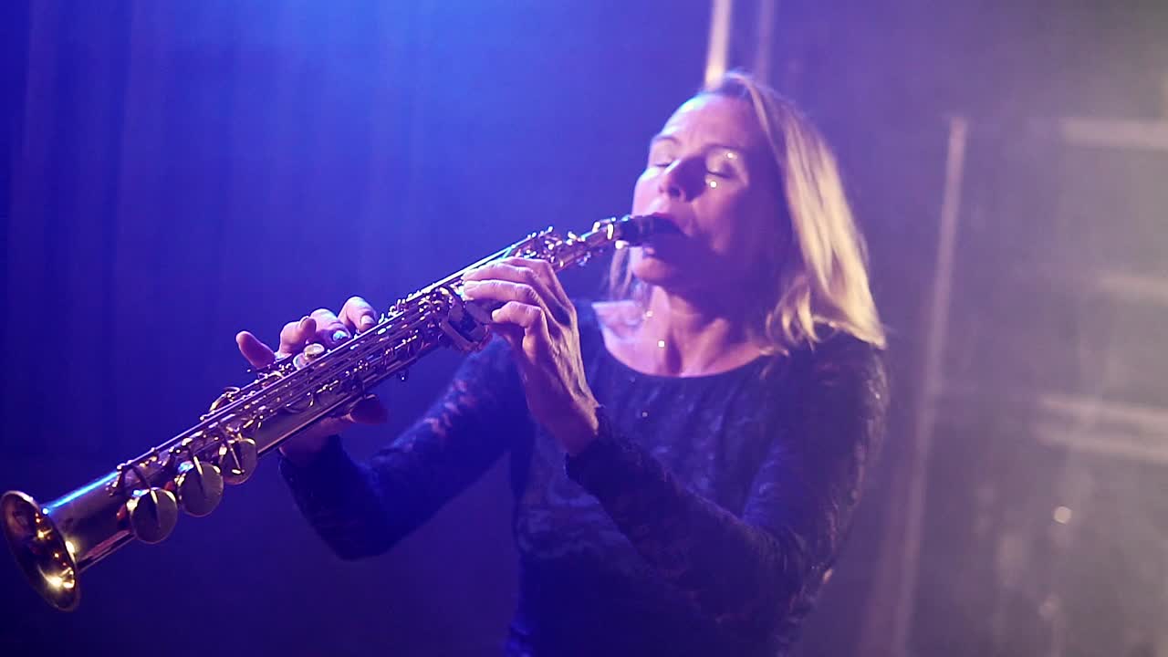 나이트 클럽의 네온 스포트라이트에서 트럼 ⁇ 을 연주하는 여성의 실루 ⁇