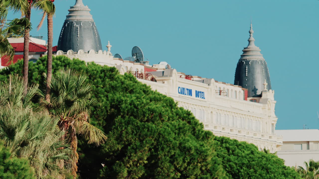 Cannes, France - October 4, 2025: Elegant view of the Carlton hotel surrounded by lush green palm trees under clear blue sky