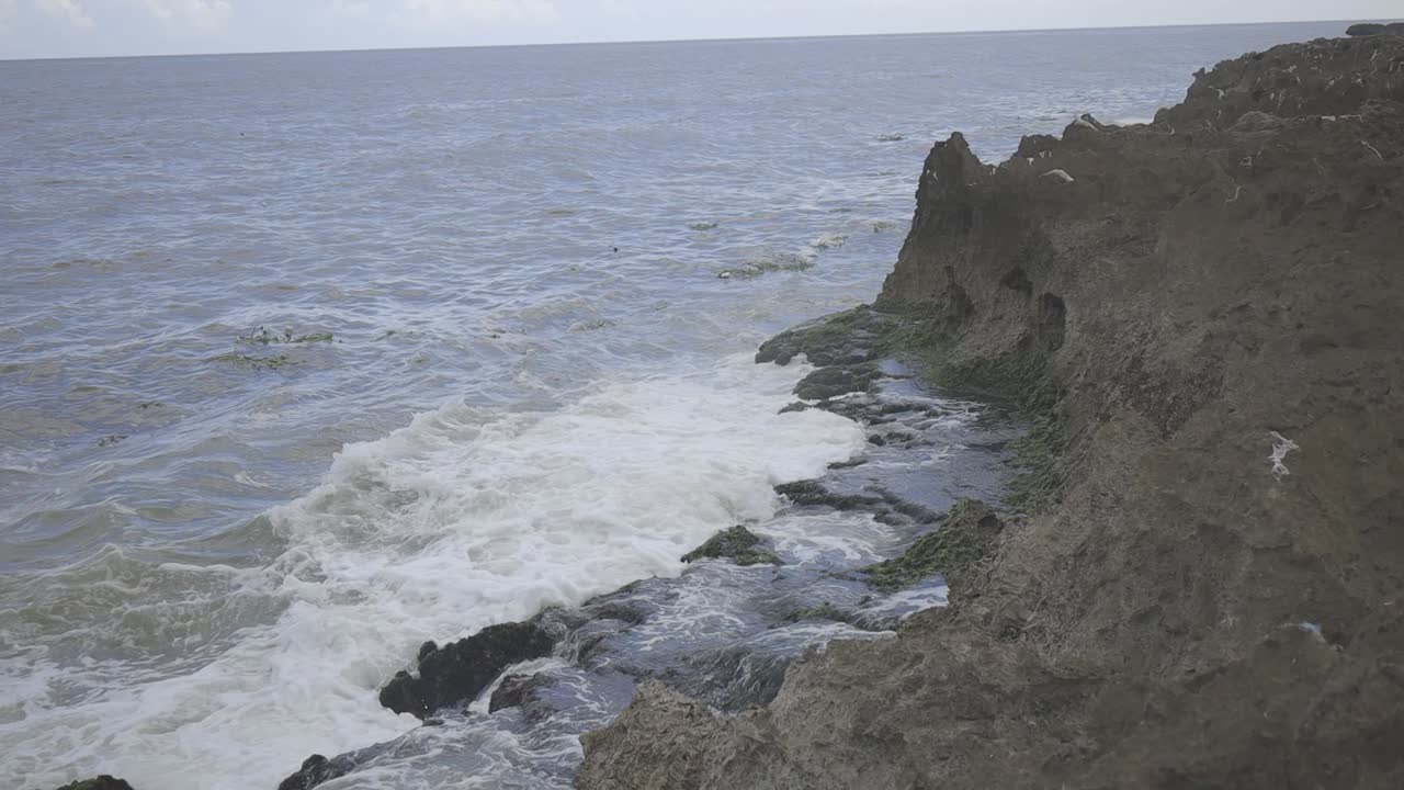 vista de las olas del océano chocando contra las rocas costeras escarpadas, video crudo c-log 8bits