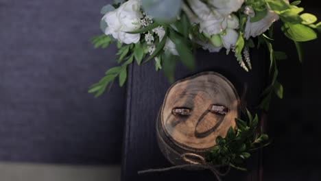 beautiful wedding rings lie on wooden stand with wedding bride's bouquet