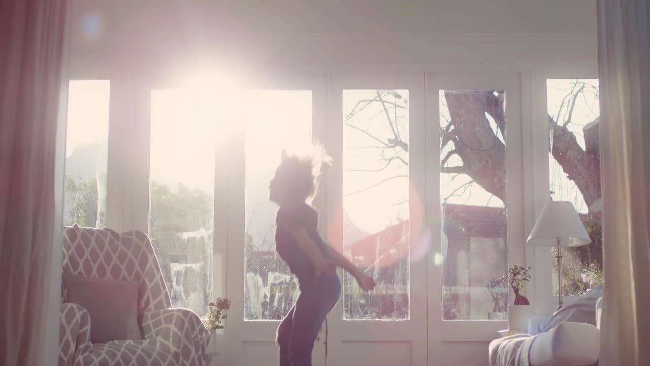 행복한 작은 소년은 소파에서 뛰어내리고 재미있게 가짜 게임을 하고 있습니다. 유쾌한 분위기의 아이는 주말 아침을 집에서 즐기고 있습니다. 태양빛이 창문을 통해 빛나고 있습니다. 어린 시절의 상상력 4k 영상