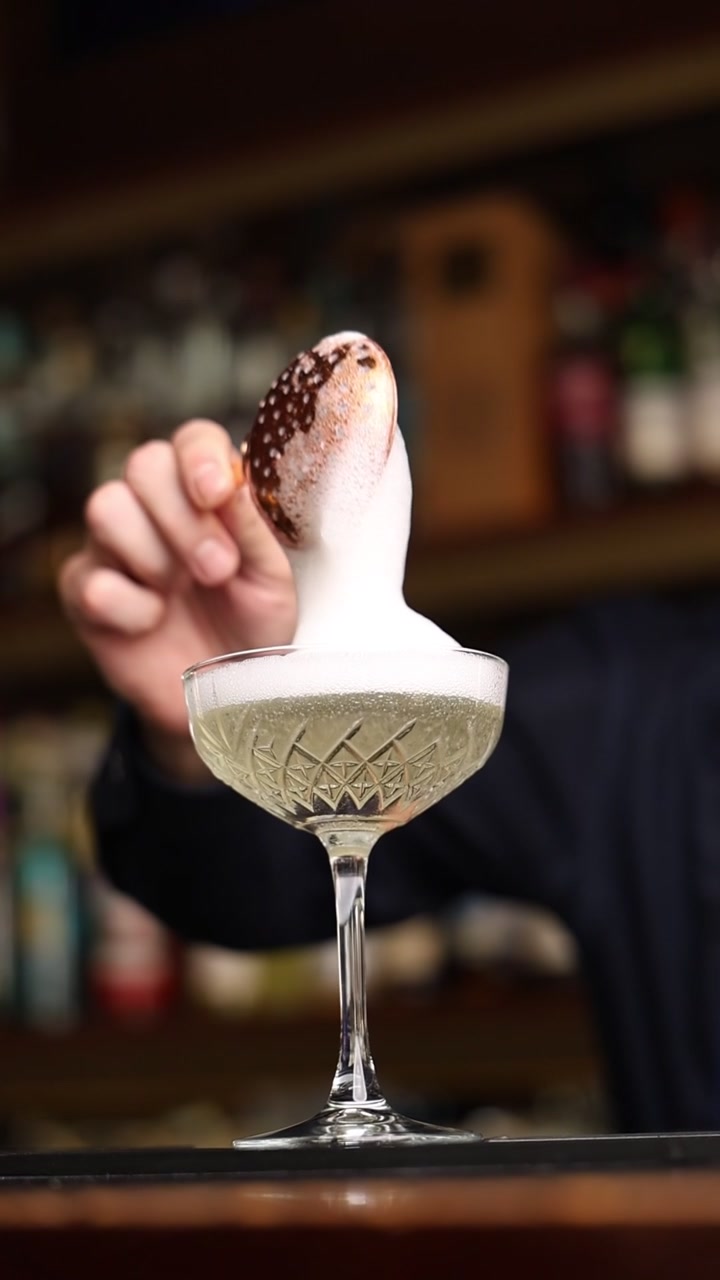 Barman che aggiunge una guarnizione di schiuma a un bicchiere da cocktail di cristallo