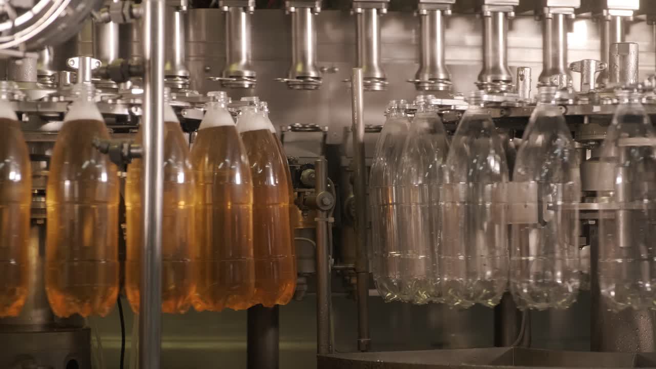 Automatisk påfyldningsmaskine fylder vand eller juice på PET-plastflasker på en moderne drikkevarefabrik