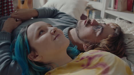couple relaxing on bed and smoking a cigarette together