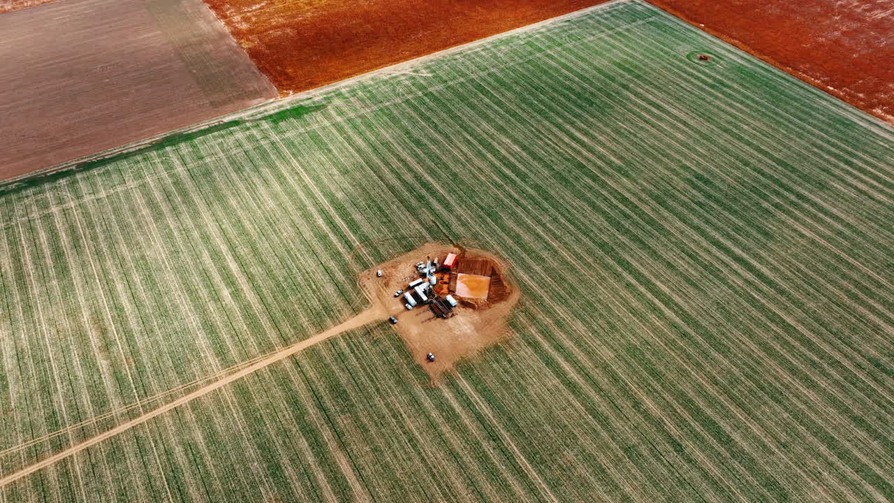 Huge field with a little site for drilling the natural mineral resources. Oil rig located in the deserted area. Top view.