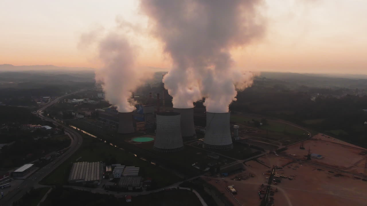 Aerial View of a Power Plant with Cooling Towers Emitting Smoke