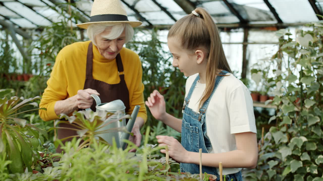Grandmother and Granddaughter Gardening in a Greenhouse