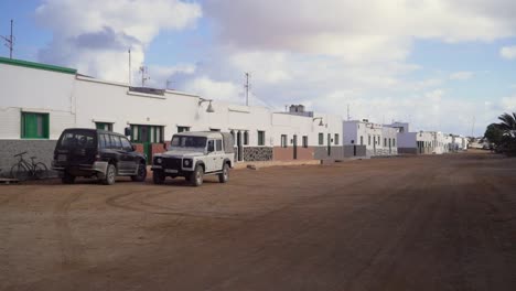 Static-shot-of-arid-and-dry-mediterranean-island-with-white-buildings-taken-during-a-cloudy-day-with-cars-in-the-shot