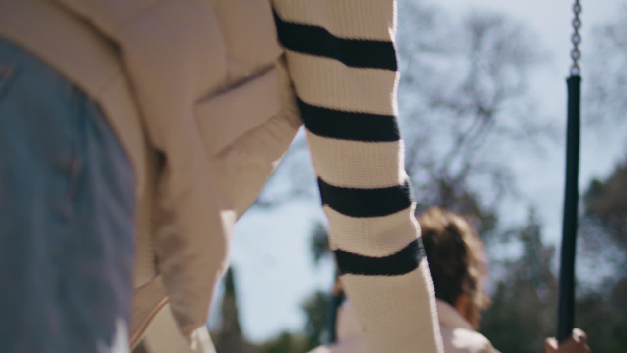 엄마가 니 파크에서 작은 소녀를 흔들고 있습니다. 여성이 스을 밀고 있습니다.