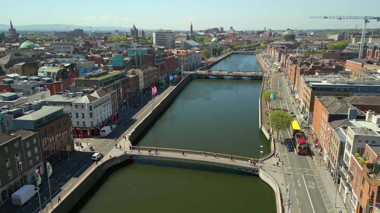 Side-on aerial video of the River Liffey, various bridges and Dublin City Centre in Dublin, Ireland on a bright and sunny day. Filmed in 4K, 60FPS and with Rec709 color.