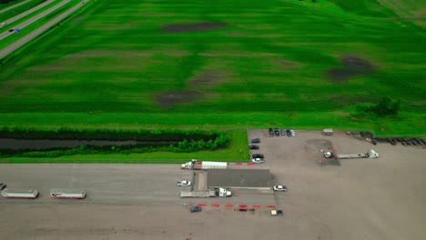 Aerial view of stepdeck trucks loading freight at a rural logistics facility, Minnesota