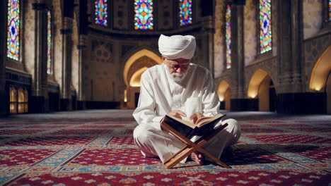 elderly muslim man reading quran in a mosque