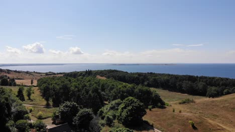 Vista-Aérea-De-La-Costa-De-Sejerøbugten-Con-Colinas,-Campos-Y-Océano