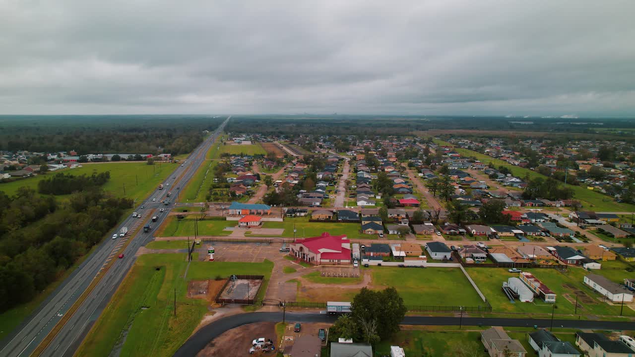 un tranquilo barrio suburbano fuera de nueva orleans, donde las casas se alinean en carreteras húmedas bajo un cielo nublado.