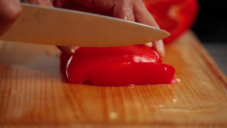 pimiento rojo cortado en cámara lenta sobre una tabla de cortar de madera