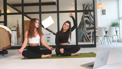 dos mujeres haciendo yoga en casa a través de clases en línea