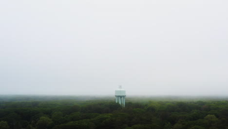 drone shot of town water tower above green trees with low visibility foggy weather hd 30p