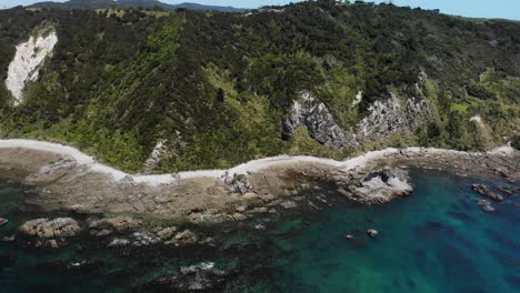 mangawhai heads aerial shot on a sunny day, flying forward to the shore showing a typical new zealand seascape and foreshore