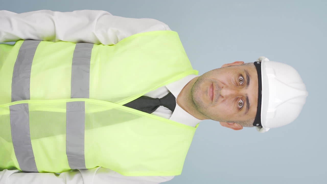 vídeo vertical del ingeniero mira a la cámara y hace una señal de alto.